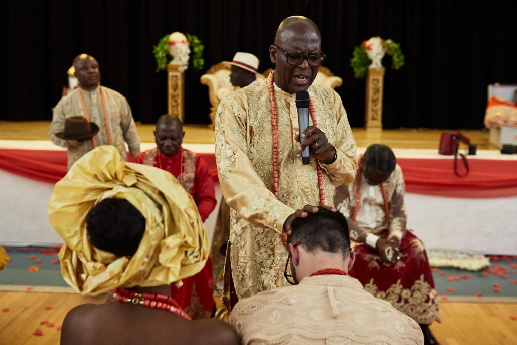 Elder speaking over the kneeling couple on stage