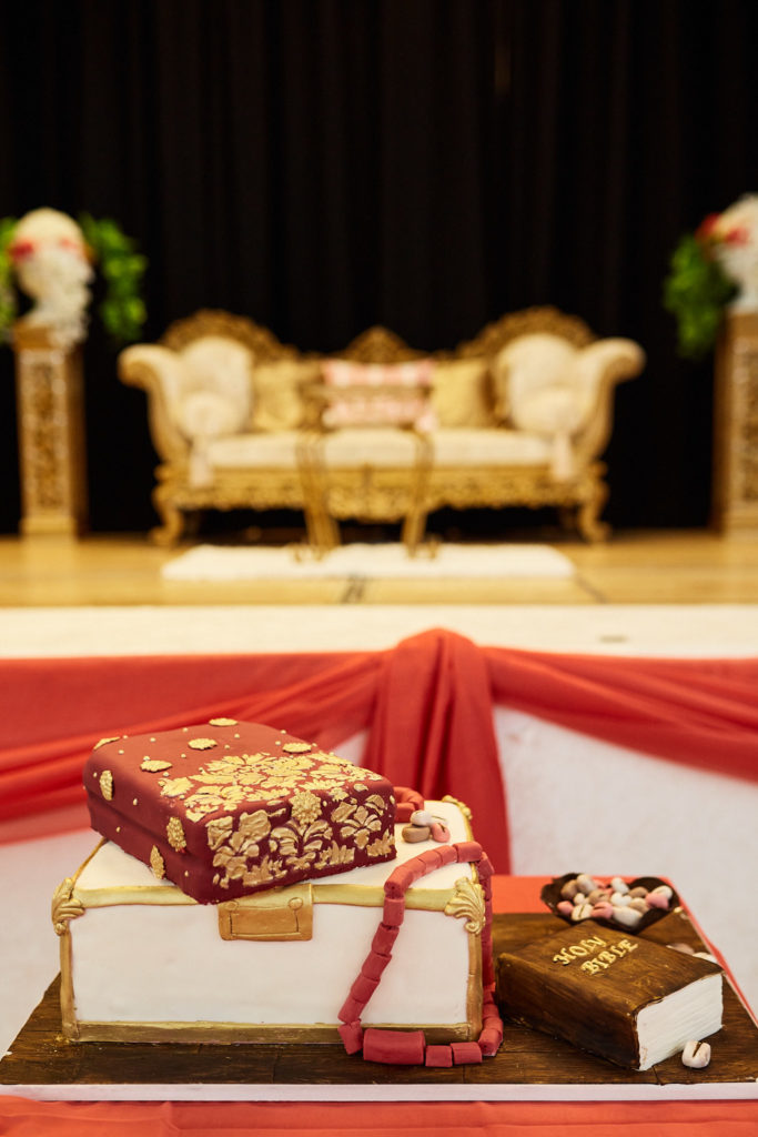 Wedding cake shaped like traditional gift boxes in front of the gold stage sofa
