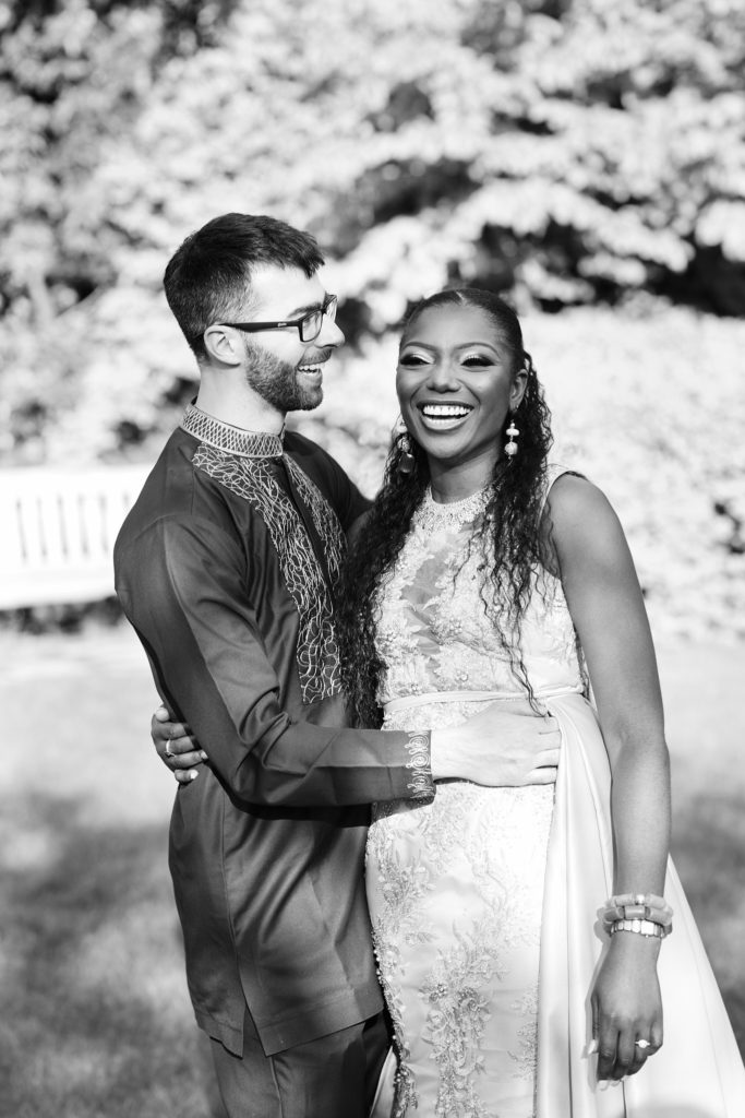 Black and white photo of the bride and groom smiling together in the garden