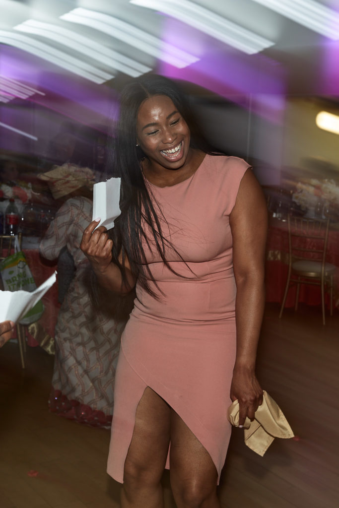 Wedding guest in a pink dress laughing as she dances