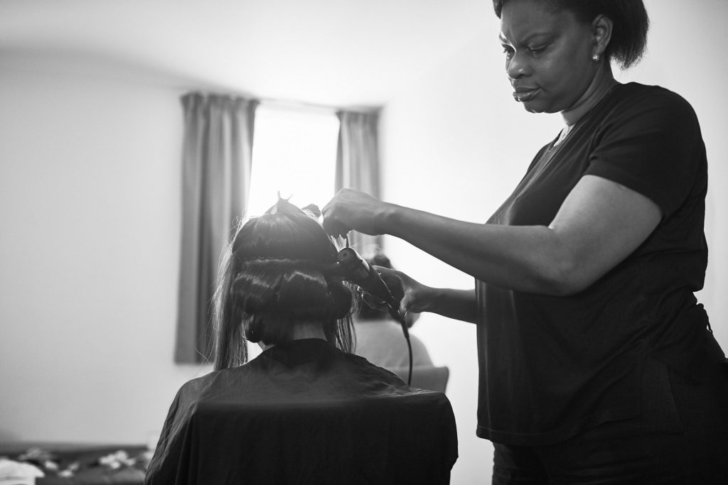 Black and white photo of a stylist doing a guest's hair
