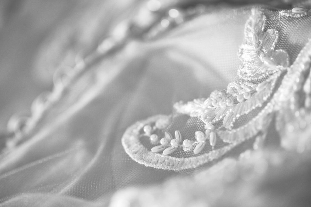 Black and white close-up of beaded lace detail on the wedding dress