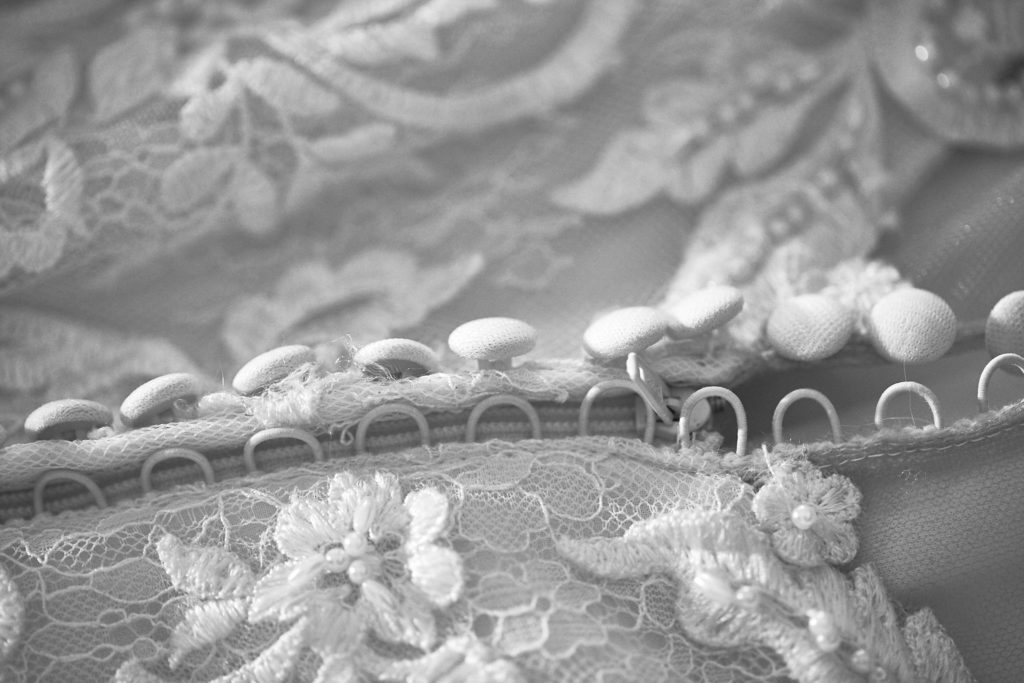 Black and white close-up of the beaded lace edge of the wedding dress