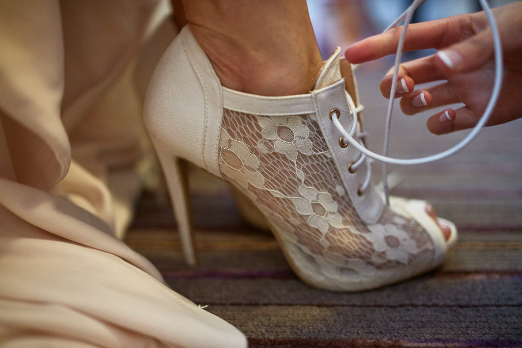 Close-up of the bride's white lace peep-toe ankle boot