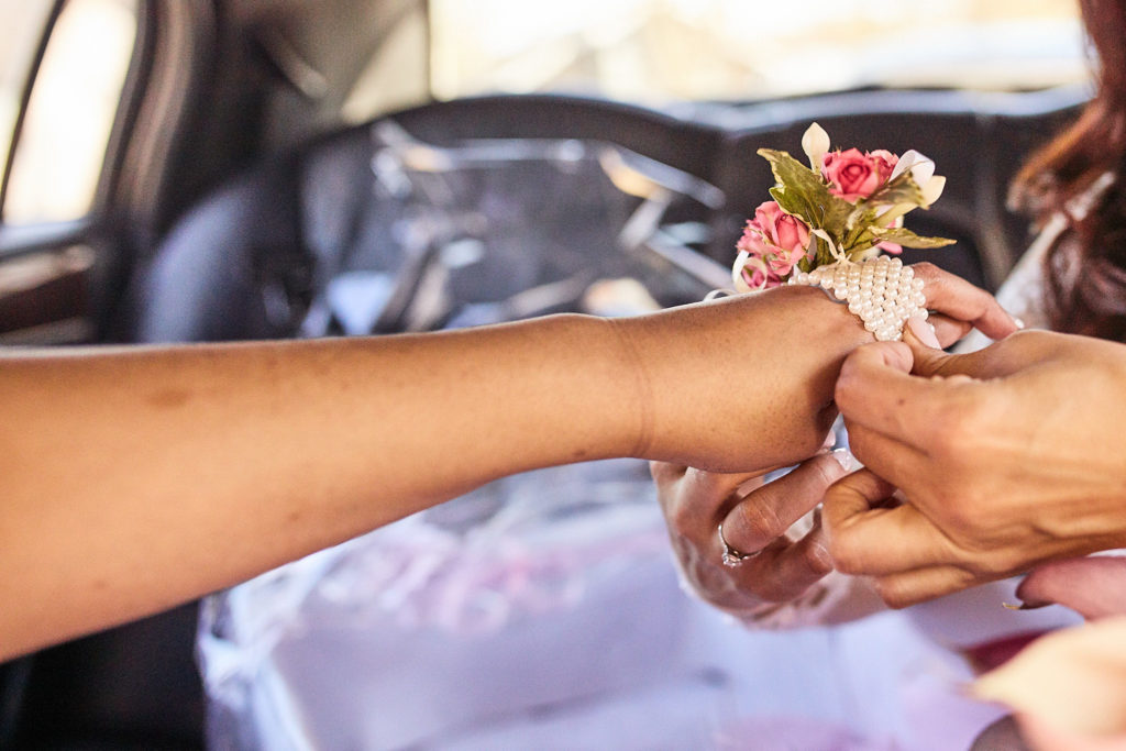 Wrist corsage of pink flowers being tied on