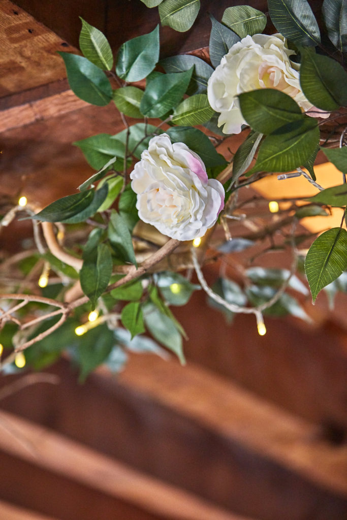 White roses and fairy lights wound round an oak beam