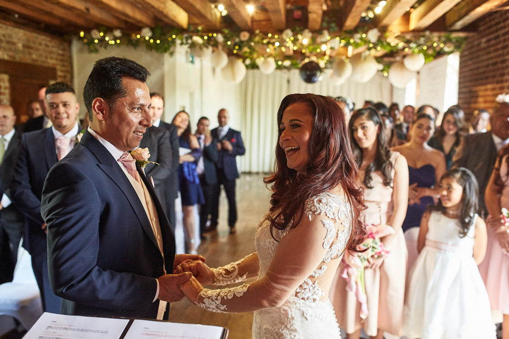Bride and groom laughing as they face each other during the ceremony