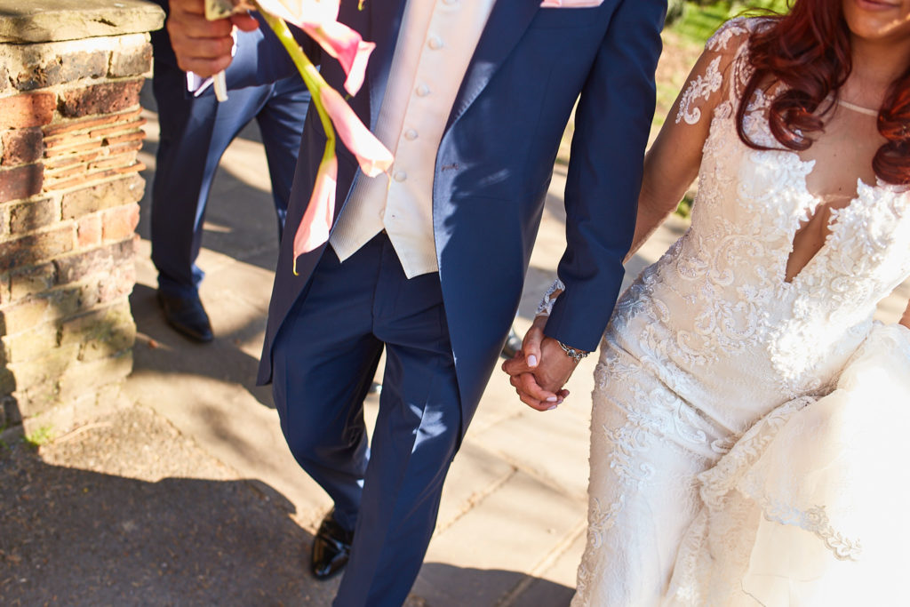 Close-up of the bride and groom holding hands as they walk