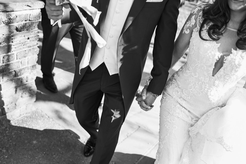 Black and white close-up of the bride and groom walking hand in hand