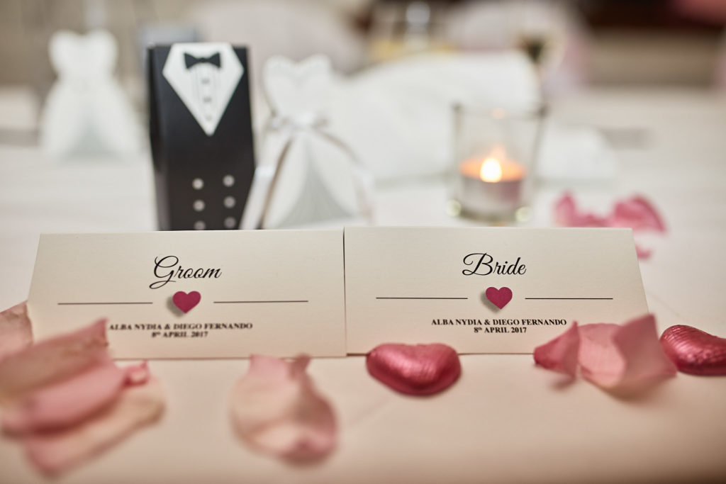 Bride and groom place cards on the top table with rose petals