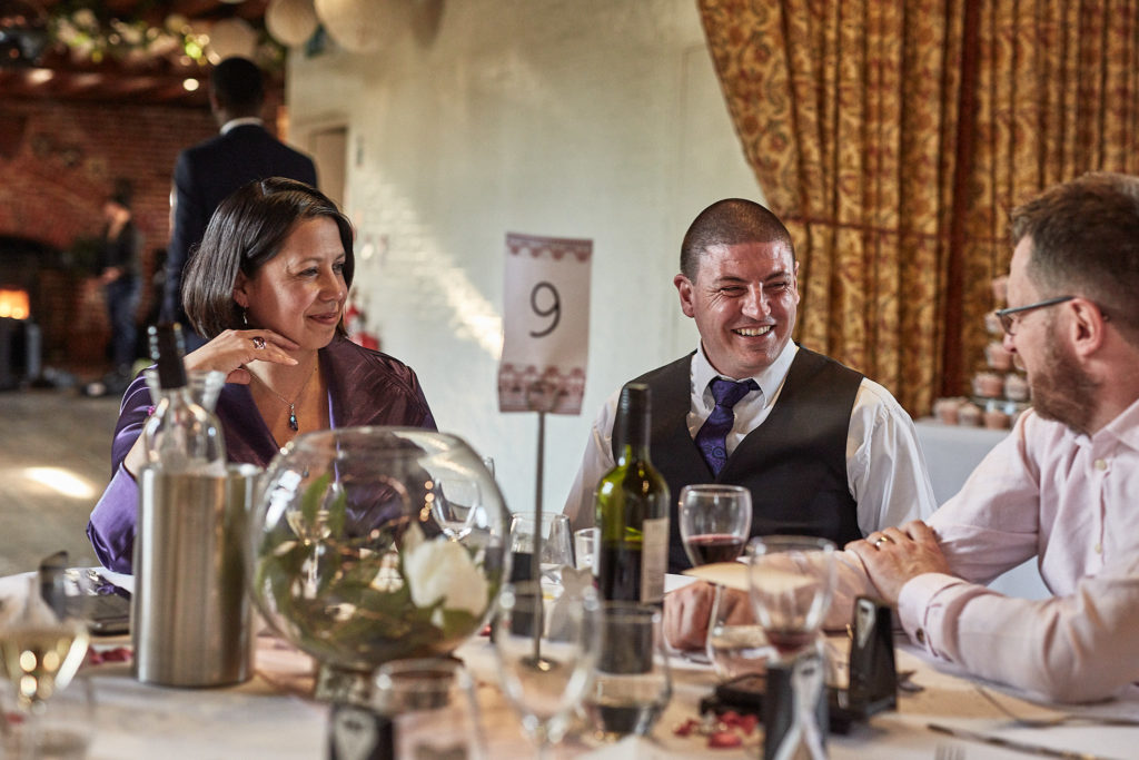 Wedding guests smiling at their table during the wedding breakfast