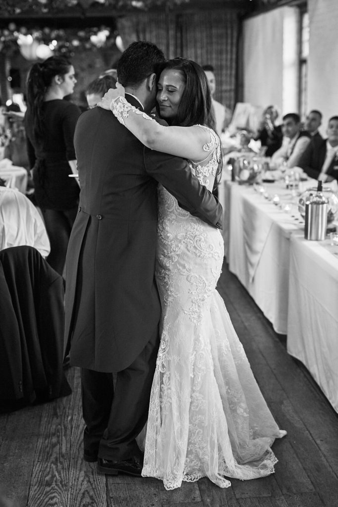 Black and white photo of the bride and groom dancing beside the top table