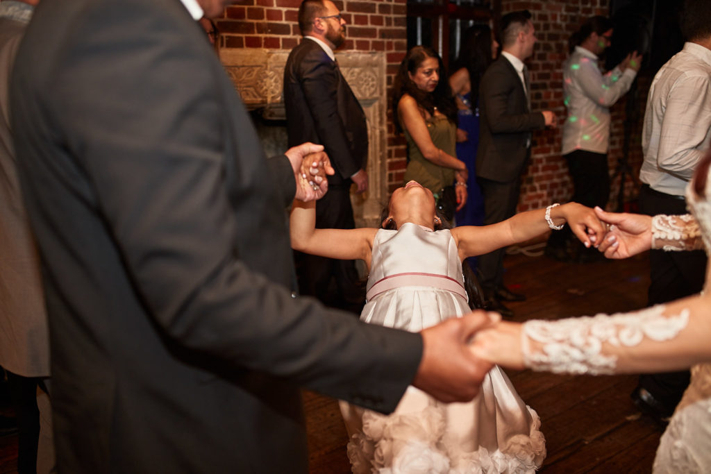 Flower girl dancing in a circle holding hands with guests