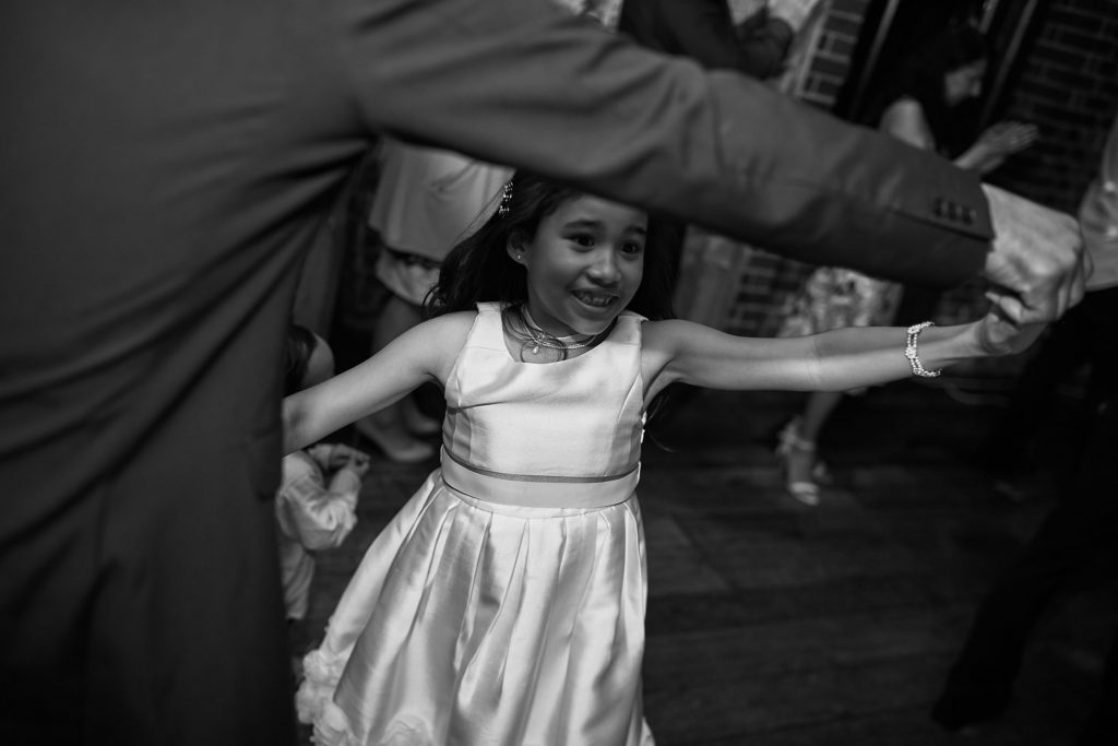 Black and white photo of a flower girl dancing with her arms outstretched