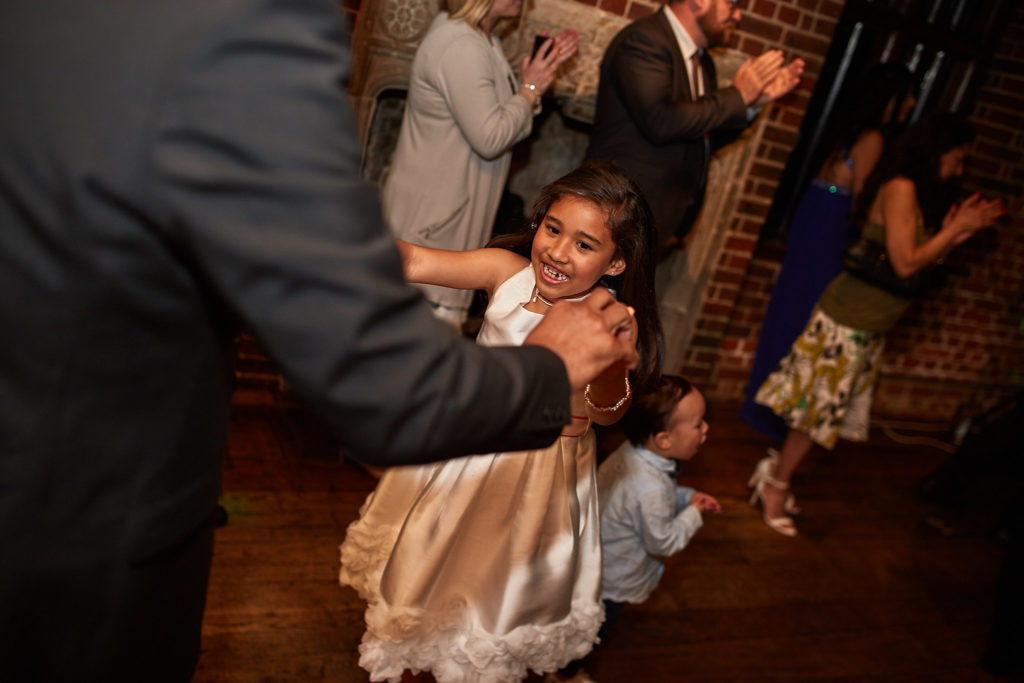 Flower girl dancing with guests on the dance floor