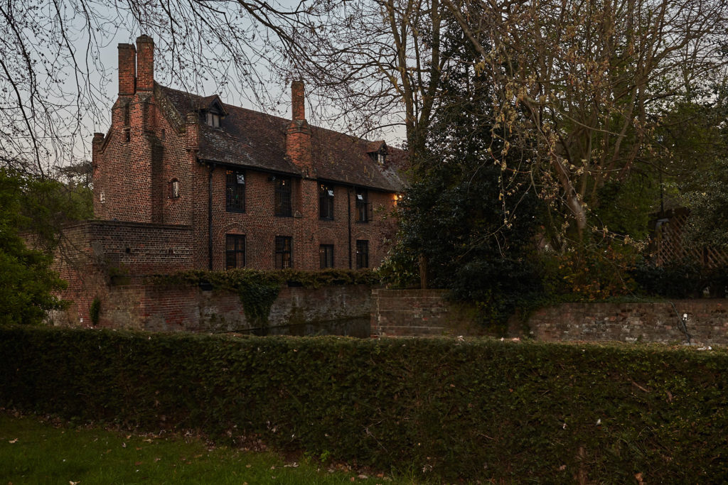 Eltham Tudor Barn seen through the trees at dusk