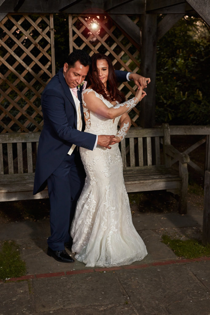 Bride and groom dancing under a wooden pergola at Eltham Tudor Barn