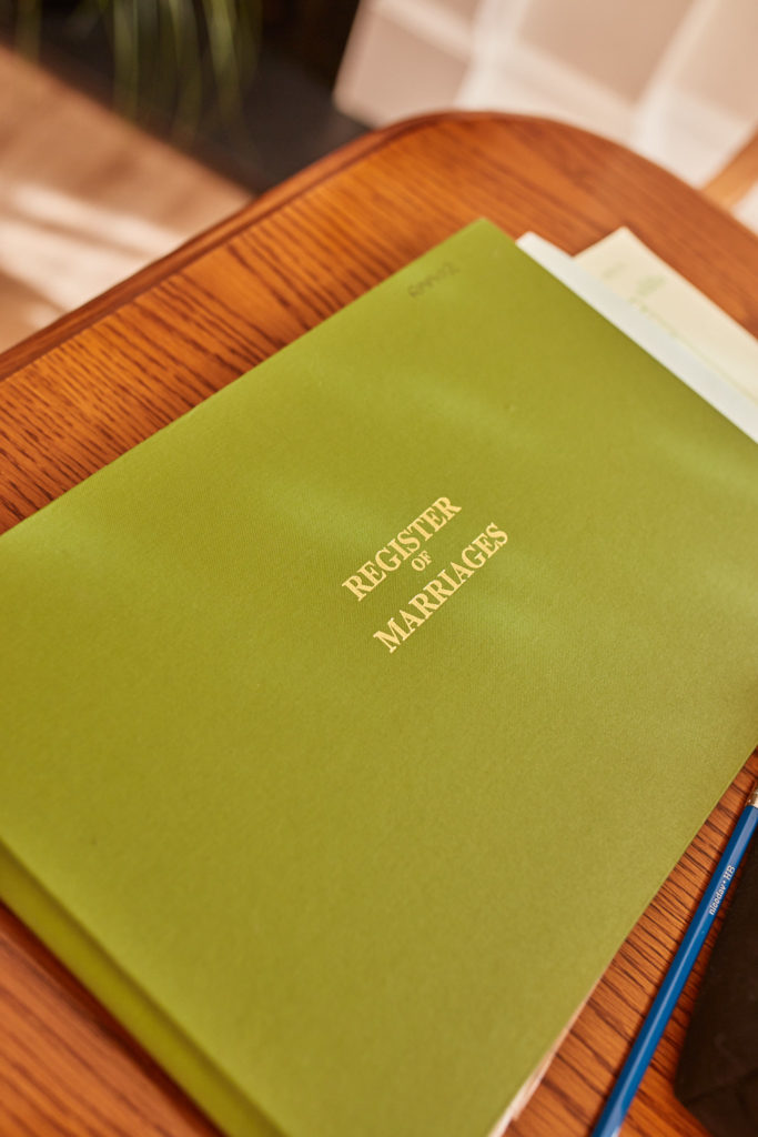 Green Register of Marriages book on a wooden desk
