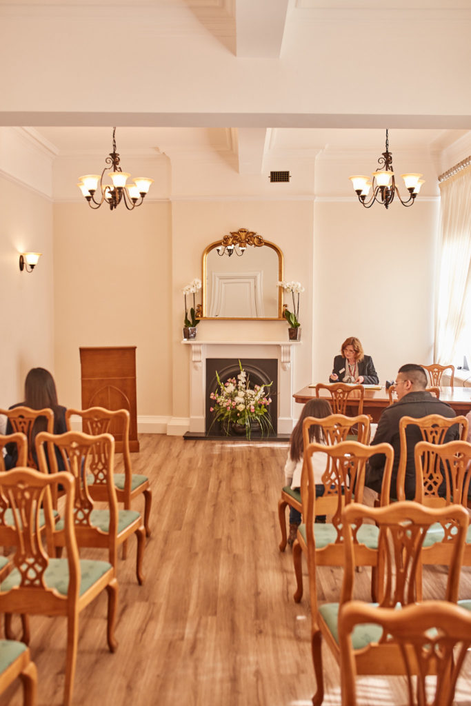 Ceremony room at Woolwich Town Hall with wooden chairs, chandeliers and a fireplace