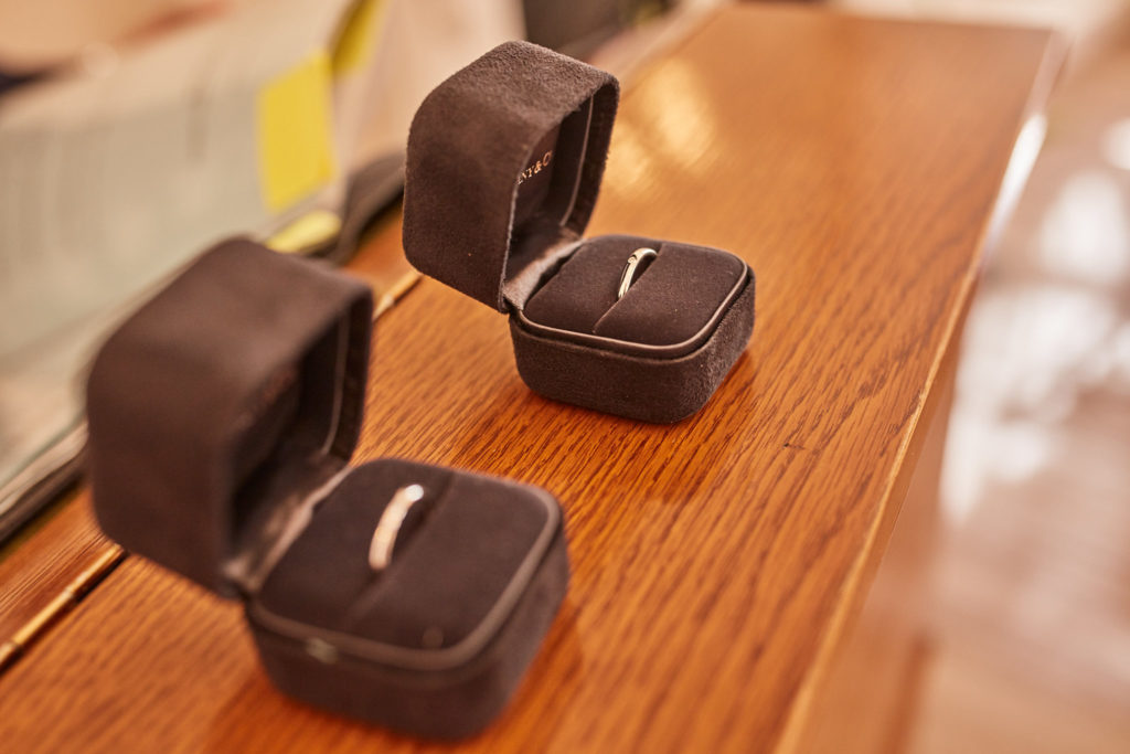 Two wedding rings in open ring boxes on a wooden table