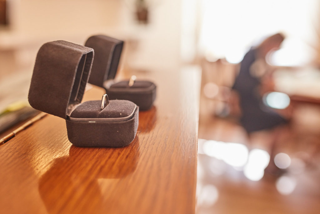 Wedding rings in their boxes with the registrar blurred behind