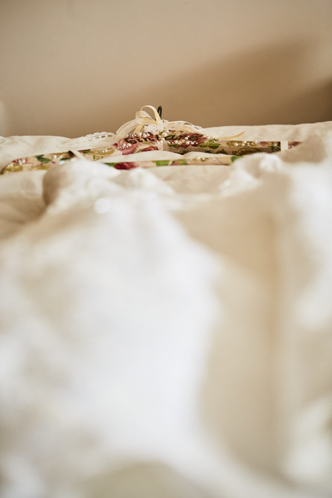 Close-up of the wedding dress fabric with a floral hanger behind