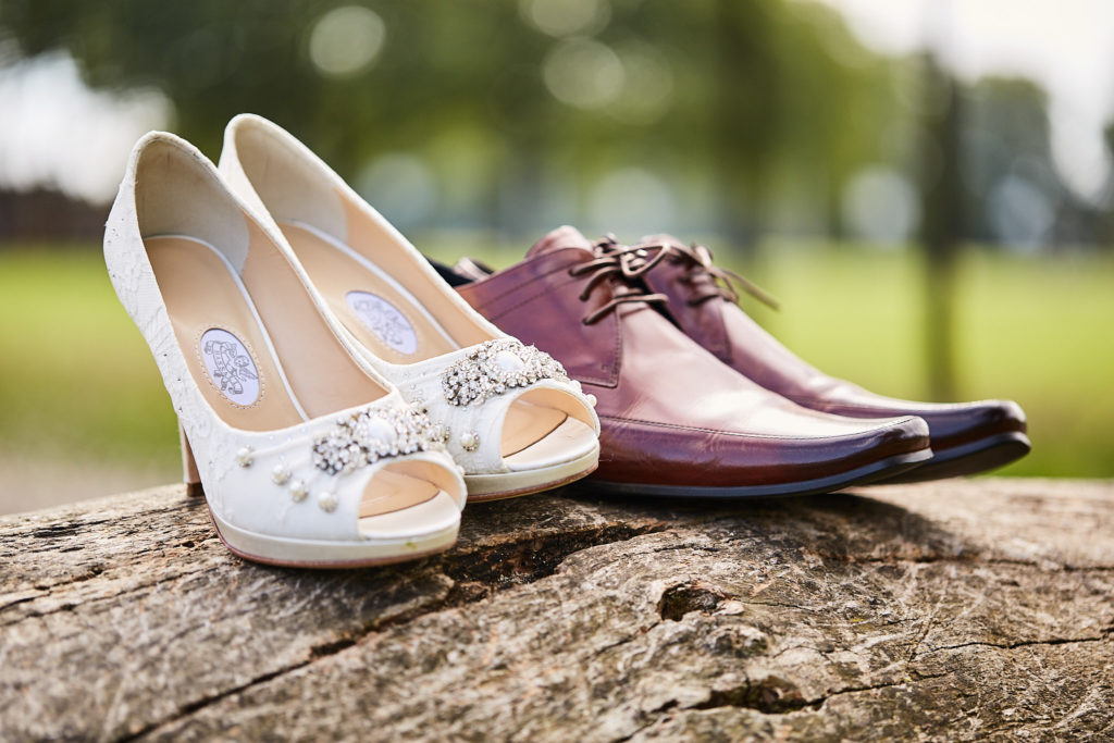 Ivory bridal shoes and burgundy brogues on a log