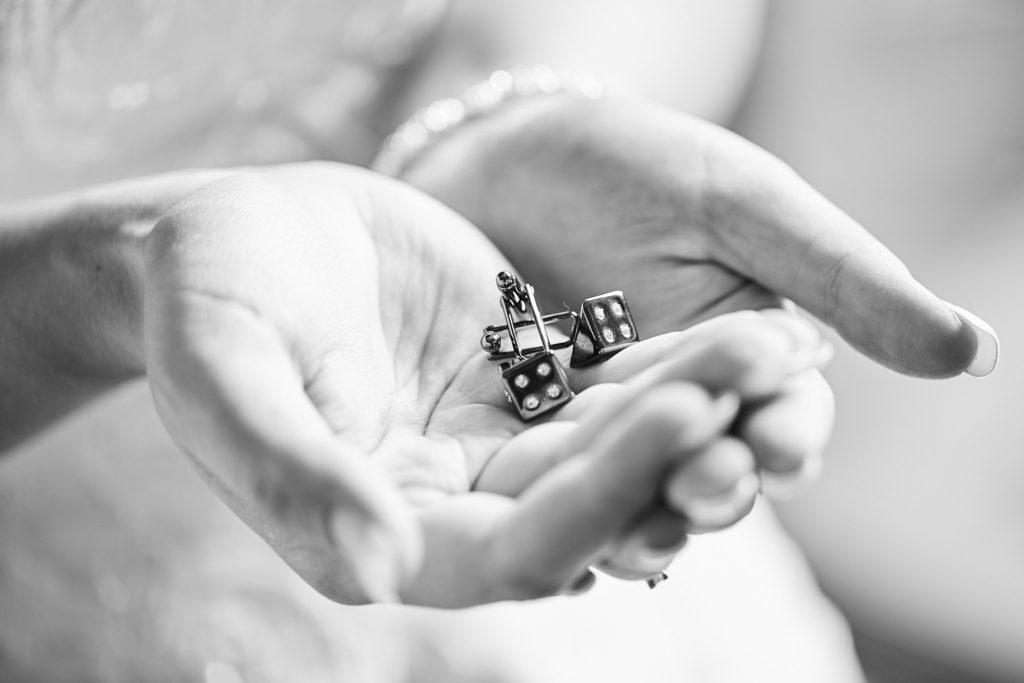 Black and white close-up of cupped hands holding a pair of cufflinks