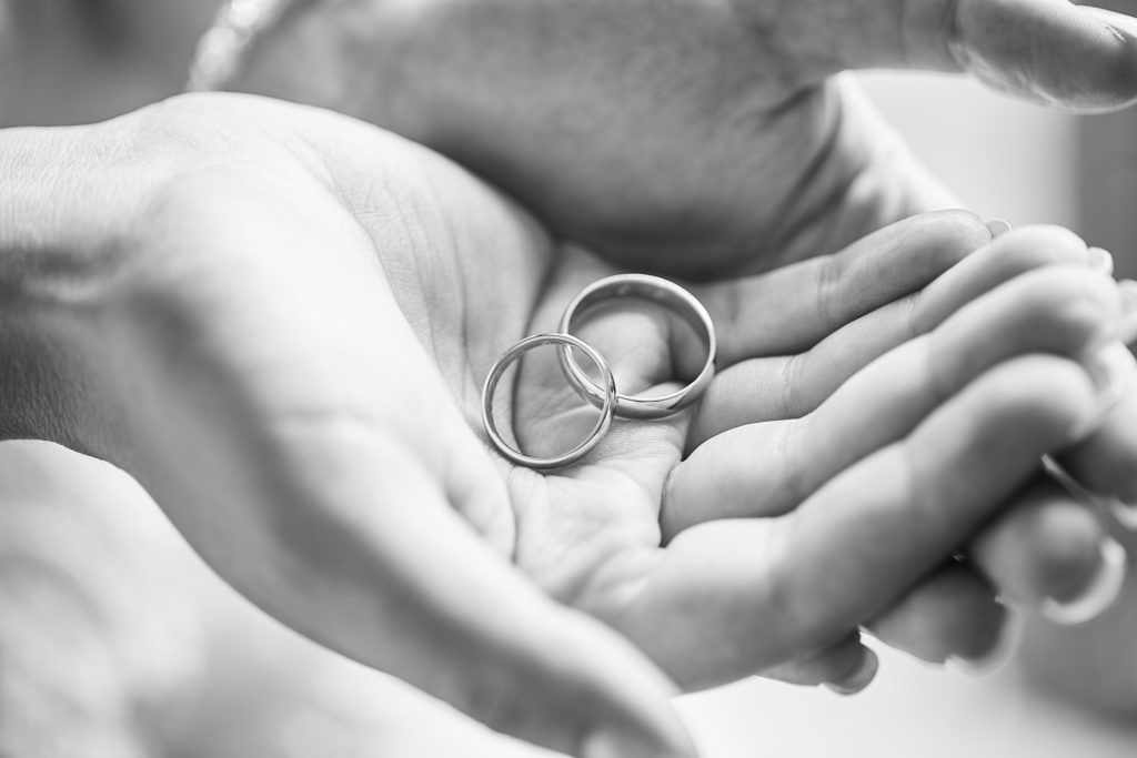 Black and white close-up of wedding rings held in cupped hands