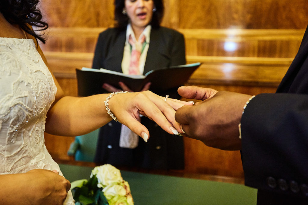 Close-up of the wedding ring being placed on the bride's finger in front of the registrar