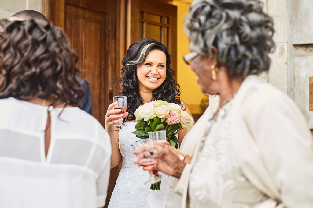 Bride smiling with her bouquet as guests congratulate her
