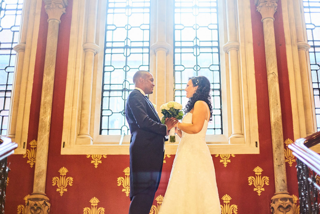 Bride and groom in front of a tall Gothic window at the St Pancras Hotel, London