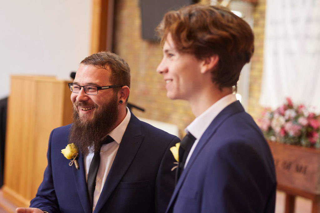 Groom and best man in navy suits waiting at the front of the church