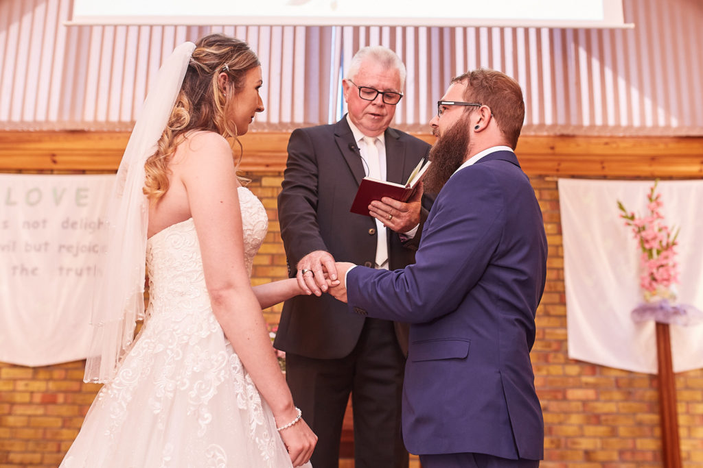 Bride and groom holding hands in front of the minister during their wedding ceremony