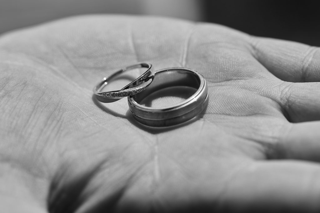 Black and white photo of wedding rings in the palm of a hand