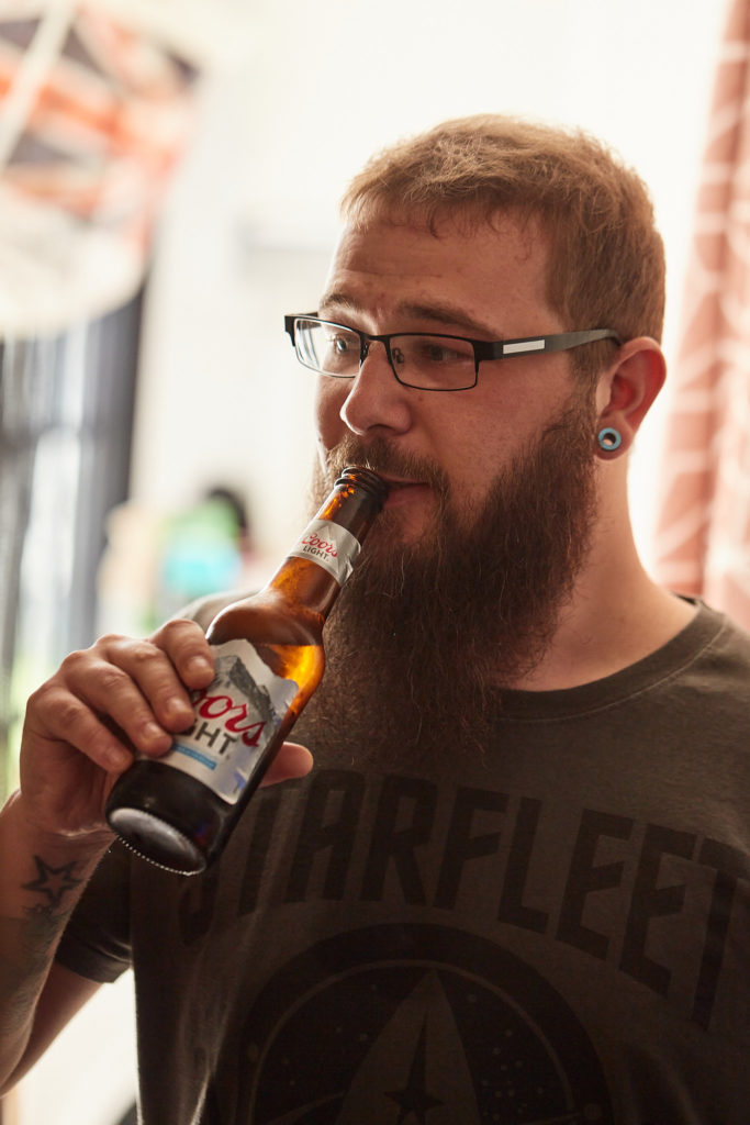 Bearded groom in glasses drinking a bottle of beer as he gets ready