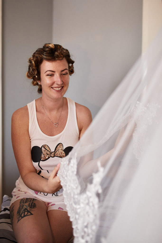 Bride laughing in a "Bride" vest top with her veil in the foreground