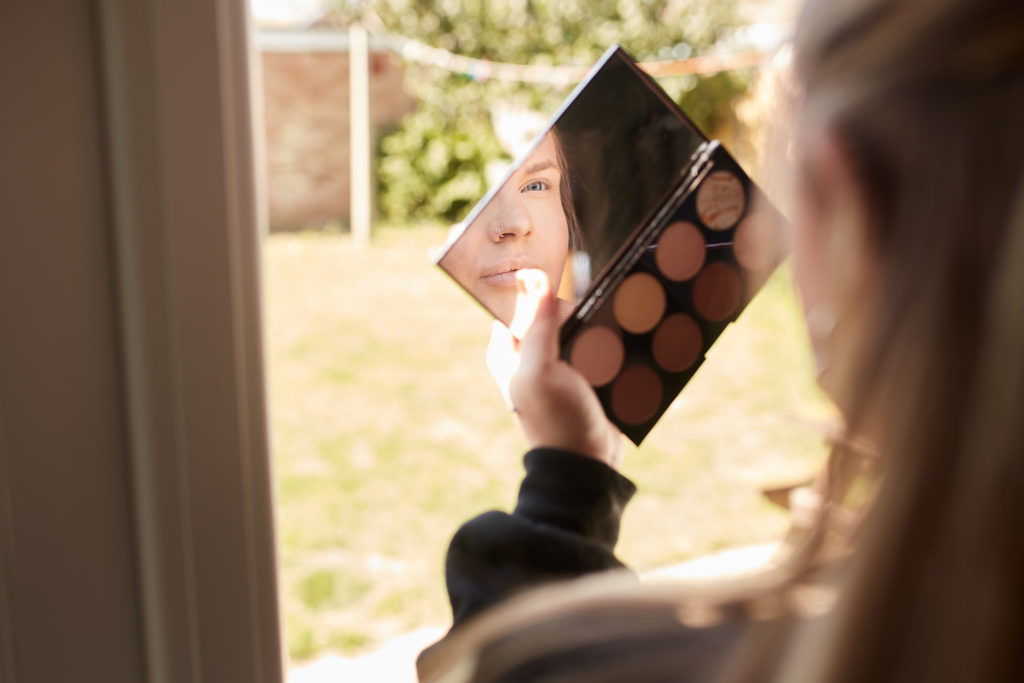 Make-up artist holding an eyeshadow palette beside a window