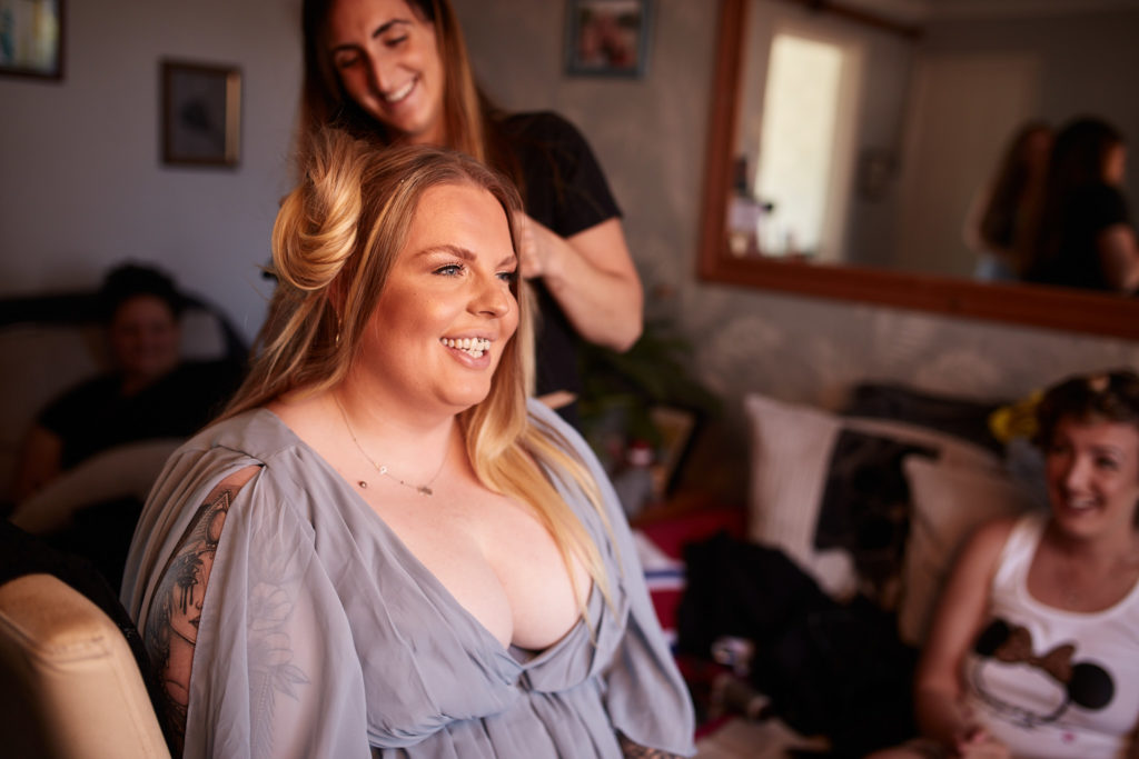 Bridesmaid sitting for her make-up with friends around her