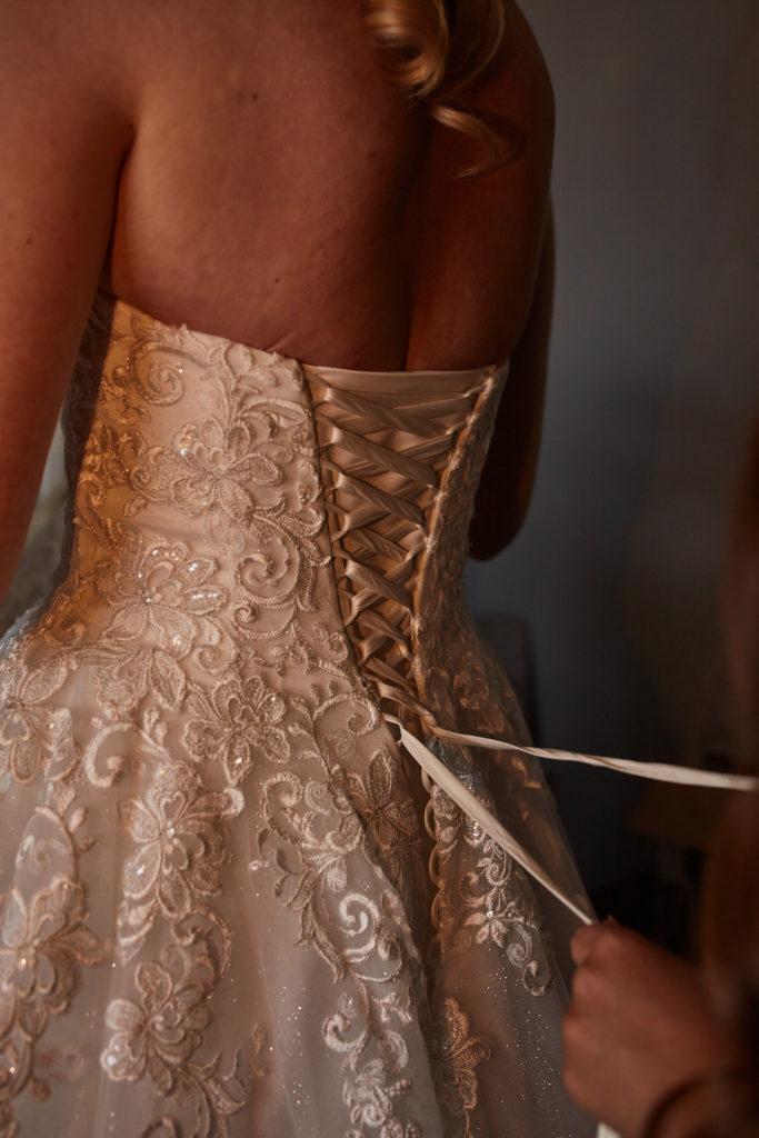 Close-up of the lace-up back of the wedding dress being tightened