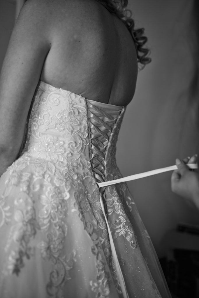 Black and white photo of the bride's corset-back dress being laced