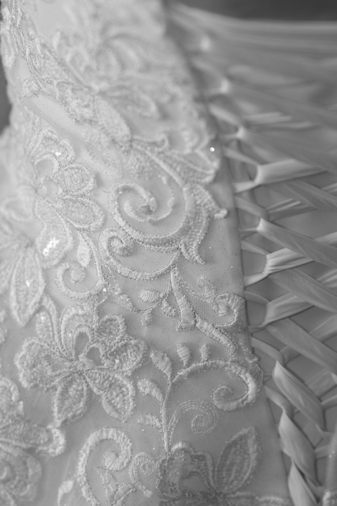 Black and white close-up of lace and ribbon lacing on the wedding dress