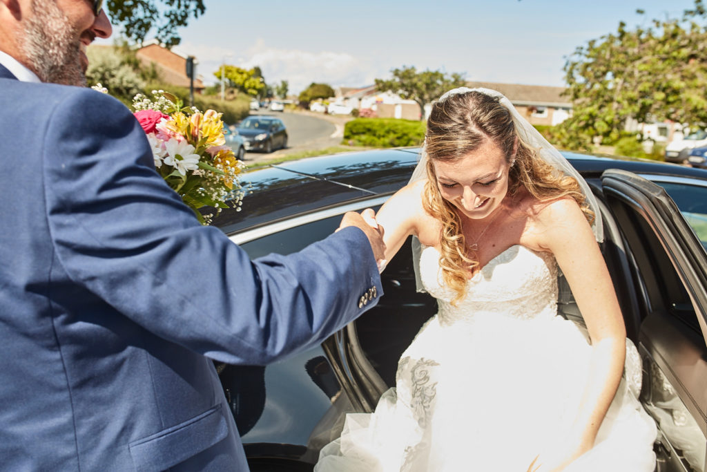 Bride being helped out of the wedding car