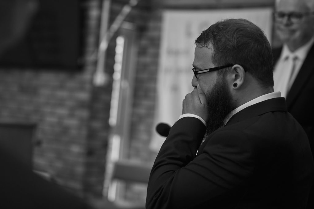 Black and white photo of the groom wiping away a tear