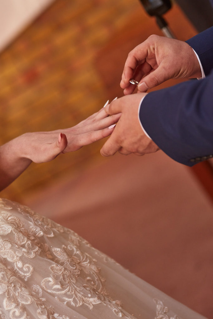 Close-up of the wedding ring being placed on the bride's finger