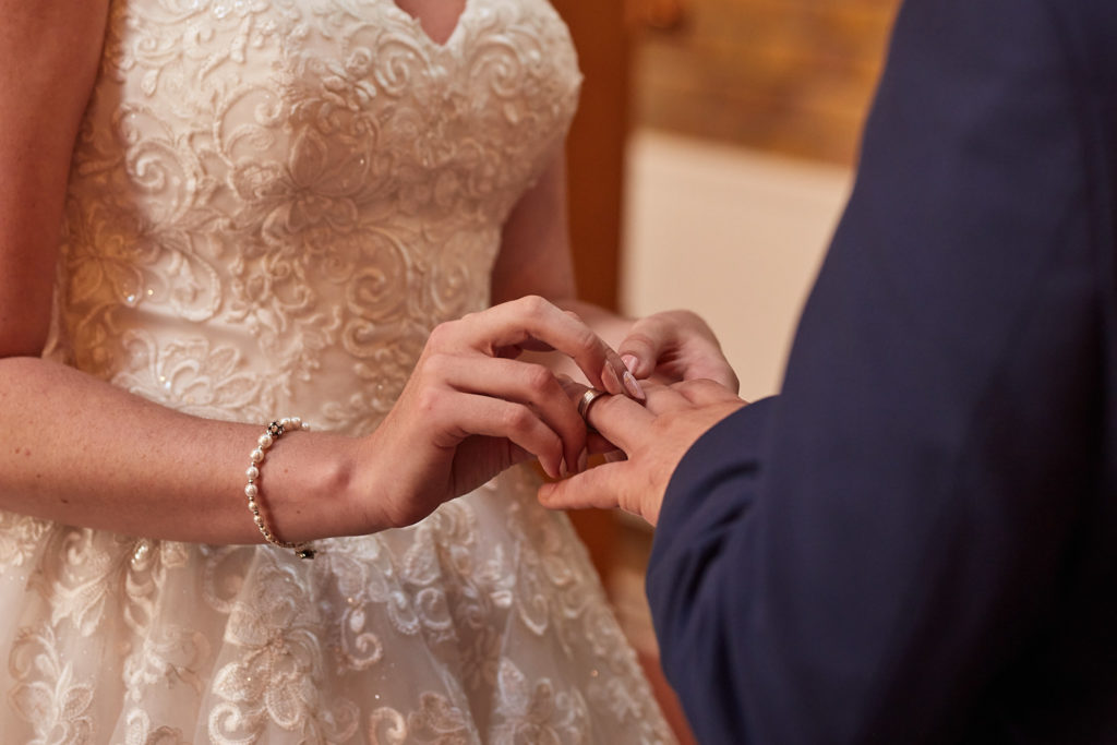 Close-up of the bride placing the ring on the groom's finger