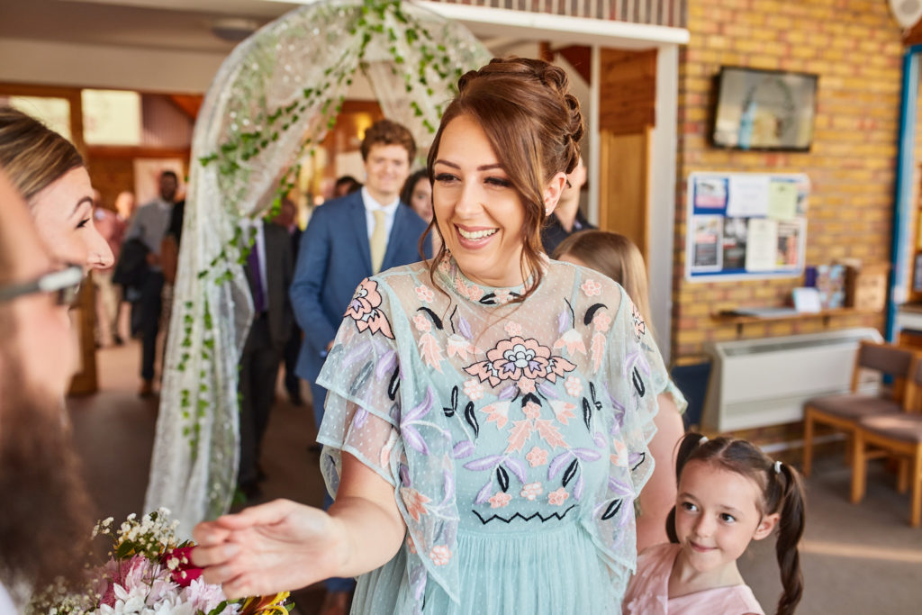 Wedding guest in a pale blue embroidered dress greeting the couple after the ceremony