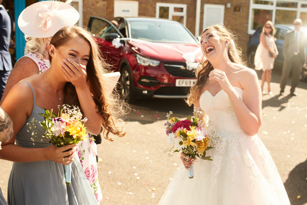 Bride and bridesmaid laughing with their bouquets after the ceremony