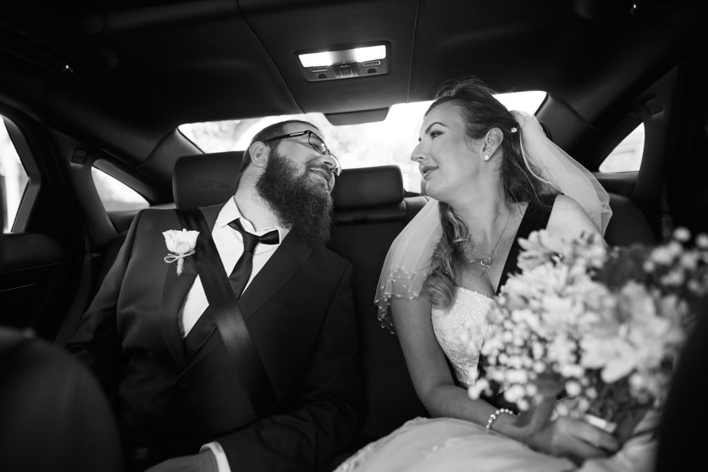Black and white photo of the bride and groom laughing in the wedding car