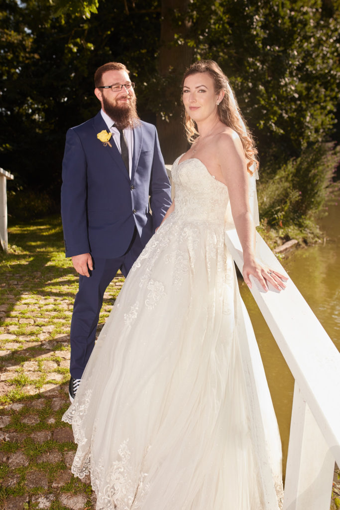 Bride and groom standing by a white bridge at Villiers Barn in evening sun